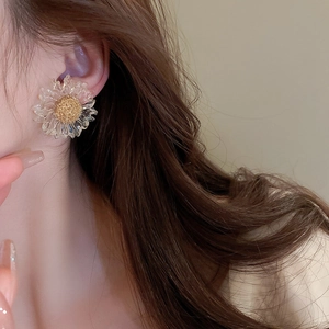 Close-up of model wearing transparent daisy flower earrings with gold textured centers