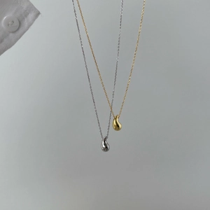 Detail view of teardrop pendants in gold and silver finish with elegant thin chains
