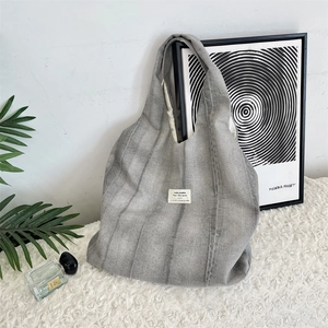 Detail of grey tie-dye canvas tote bag with woven label on soft plush carpet