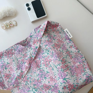 Detailed flat lay of pink floral cotton shoulder bag with simple wish woven label