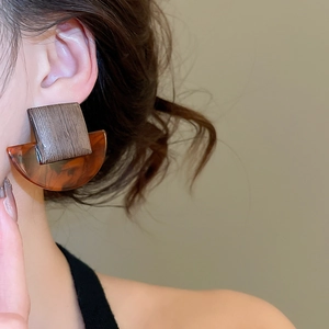 Close-up of geometric earrings with square wood grain and amber resin on model