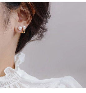 Detail of elegant gold double pearl earrings worn on ear showing fine craftsmanship