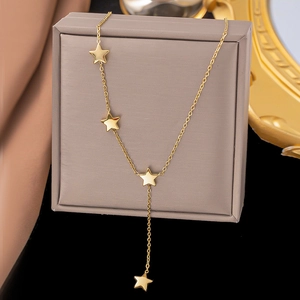 Close-up of gold star pendant Y-necklace hanging on a gray jewelry box with silk fabric
