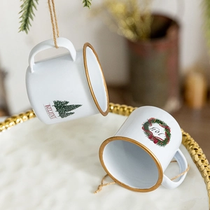 Miniature Christmas cup ornaments with Believe and Joy prints on festive gold-rimmed ceramic