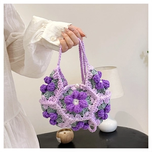 Detailed close-up of handmade crochet bag featuring purple and green 3D puff flowers