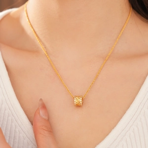 Close-up of 18k gold-plated cylinder pendant necklace with zircon and textured wheat relief