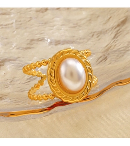 Detail of vintage gold ring with oval pearl on a textured glass tray setting