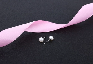 Macro detail of natural freshwater pearl earrings on elegant black textured surface
