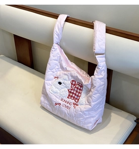 Detail of pink quilted tote bag with heart patterns and cute cartoon puppy embroidery