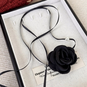 Detail of vintage black fabric rose choker with delicate ribbon and pearl accent