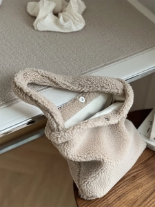 Close-up of beige fleece handbag with magnetic clasp and soft texture detail
