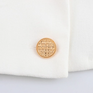 Dettaglio ravvicinato di un bottone dorato su un completo pantalone in tweed bianco