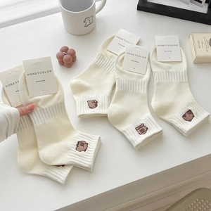 Calze in cotone bianco crema con ricamo a forma di orso e cartellino del marchio