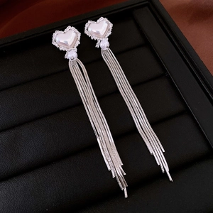 Macro detail of silver tassel earrings with heart-shaped faux pearls and rhinestone accents