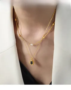 Close-up of a double-layered gold necklace with a freshwater pearl and black oval pendant