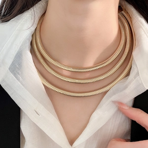 Close-up of triple-layered golden spring-style necklace featuring textured spiral design