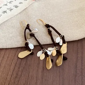 Bohemian gold and silver metal water drop fringe earrings on linen and wood background