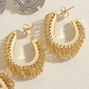 Detail of gold spiral textured C-shape hoop earrings with vintage metal finish