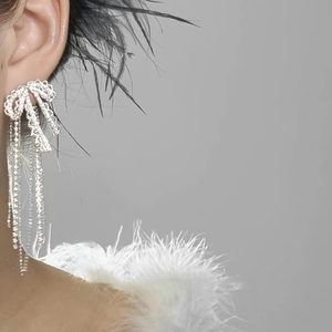 Elegante silberne Schleifenohrringe mit Zirkonia-Quasten getragen von einem Modell