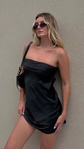 Détail d'une robe tube en satin noir montrant la texture de soie et la coupe ajustée