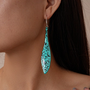 Close-up of a bohemian teardrop leaf earring with blue-green and black spotted patterns