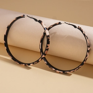 Macro detail of retro leopard print hoop earrings with vintage geometric pattern textures