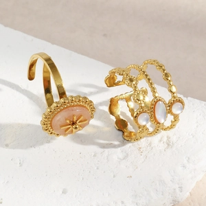 Détail de bagues plaquées or 18 carats avec pierre rose et perle sur marbre