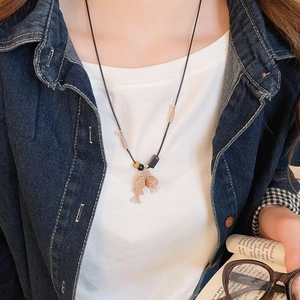 Detail of wooden fish pendant necklace with tassel on model wearing denim jacket