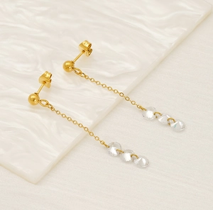 Detail of long gold tassel earrings with sparkling zircon stones on a white background