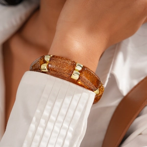 Close-up of bohemian amber resin block stretch bracelet with gold glitter and metal accents