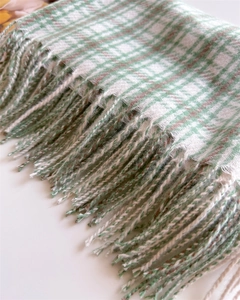 Detail shot of green and white plaid scarf featuring soft texture and long fringe tassels