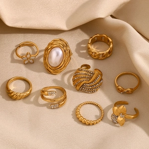 Detailed close-up of 9-piece gold ring set with pearls and crystals on beige silk