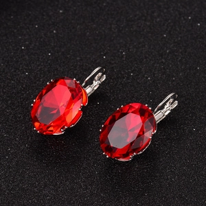 Macro shot of red oval faceted gemstone earrings on a black glitter background