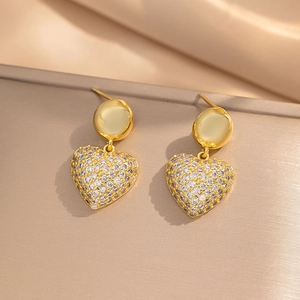 Gold heart drop earrings with white zircon pavé on a champagne satin background