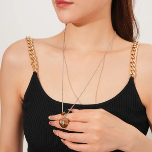 Detail of a brown resin heart pendant necklace with a silver pattern on a model