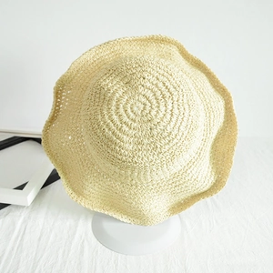 Close-up of beige woven straw hat featuring a detailed wavy brim and rustic texture
