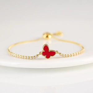 Macro shot of gold butterfly bracelet with red enamel and sparkling zircon accents