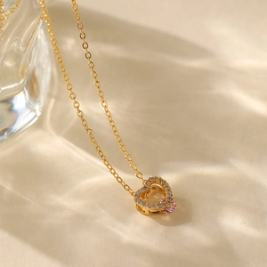 Macro shot of 18K gold plated heart pendant necklace with pink gem and pavé zircon stones