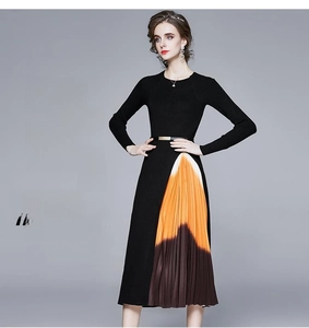 Détail d'une robe en maille ajustée avec jupe plissée orange contrastée et ceinture fine