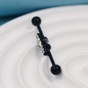 Vue détaillée du piercing industriel noir avec quatre zircons blancs sur fond bleu