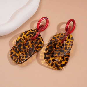 Dettaglio di orecchini pendenti in acrilico con stampa leopardata marrone e maglie rosse vivaci