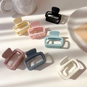 Flat lay of colorful cream-colored square hair claws scattered on a white table with props