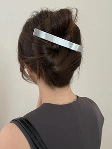 Gros plan d'une pince à cheveux en métal argenté brossé sur le chignon d'un mannequin