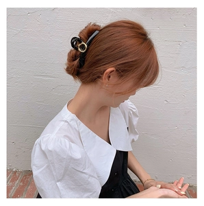 Side view of a French style black hair claw with gold geometric ring on a model