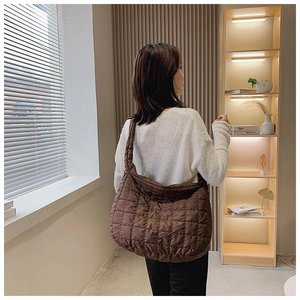 Coffee brown quilted down cotton tote bag worn by a model in a cozy indoor setting