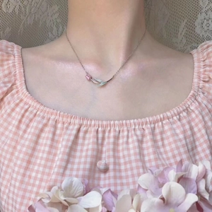 Delicate silver tulip pendant necklace on a fine chain worn by a woman with floral background
