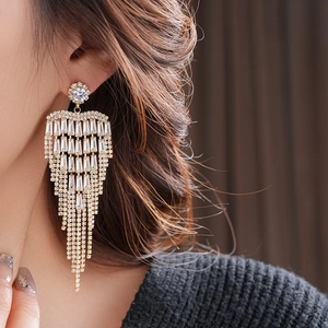 Detail of long gold earrings with baguette-cut zircon tassels on a female model