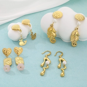 Macro detail of gold sea animal earrings with pearls and pink stone on cloud prop