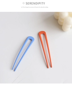 Detail view of U-shaped matte hair pins in pastel blue and coral on white background