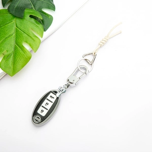 Black leather texture Nissan key fob cover with silver frame and woven lanyard accessory